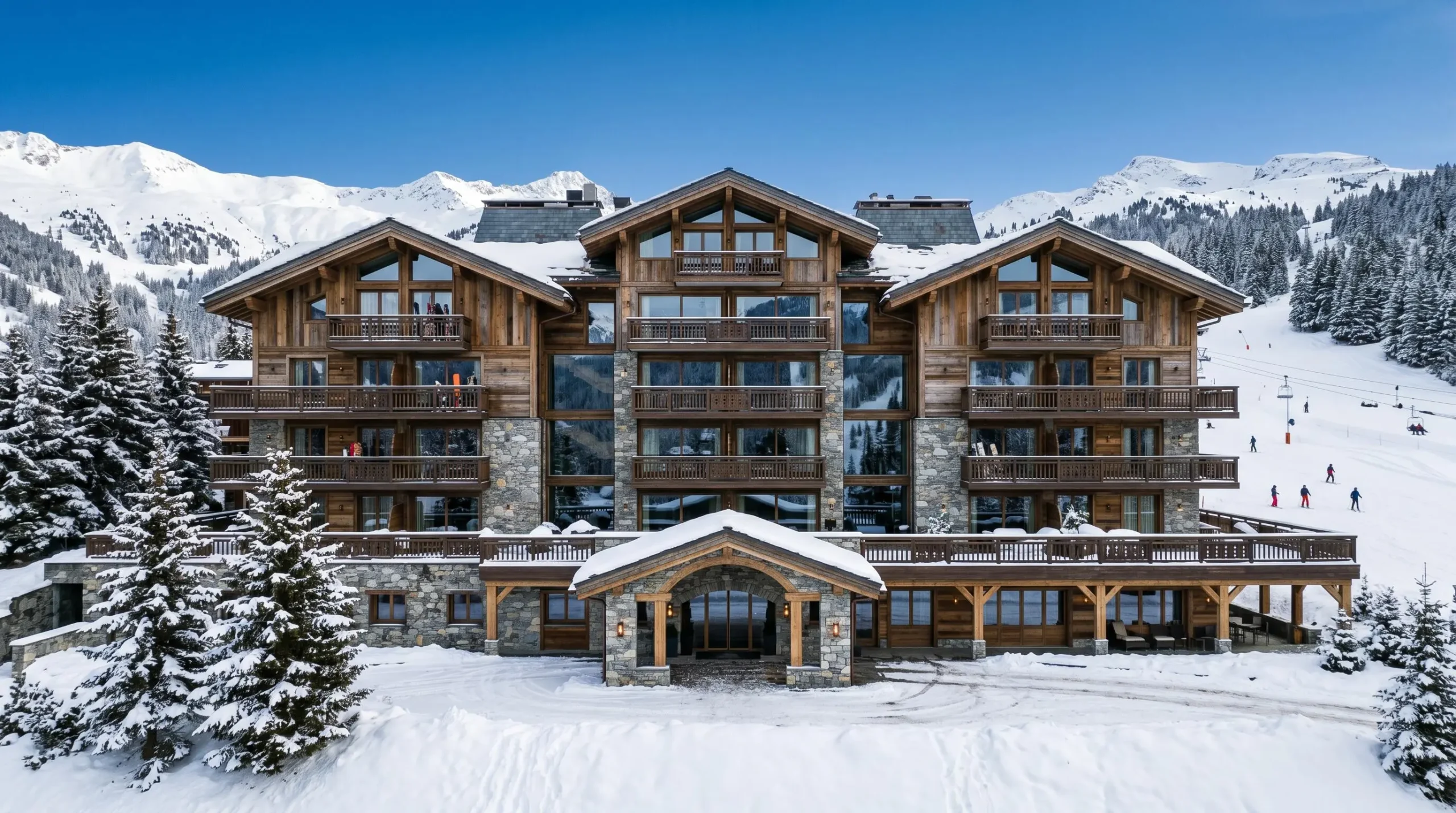 Façade extérieure d'un palace 5 étoiles à Courchevel 1850 montrant l'architecture alpine de luxe en bois noble et pierre avec grandes baies vitrées et balcons sculptés dans un environnement enneigé sous ciel bleu d'hiver